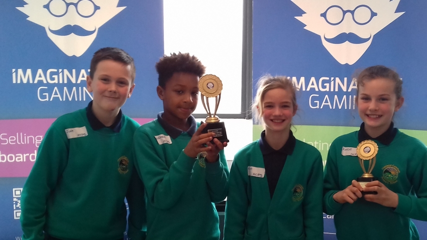 Four school children in green and black uniform holding Imagination Gaming trophies