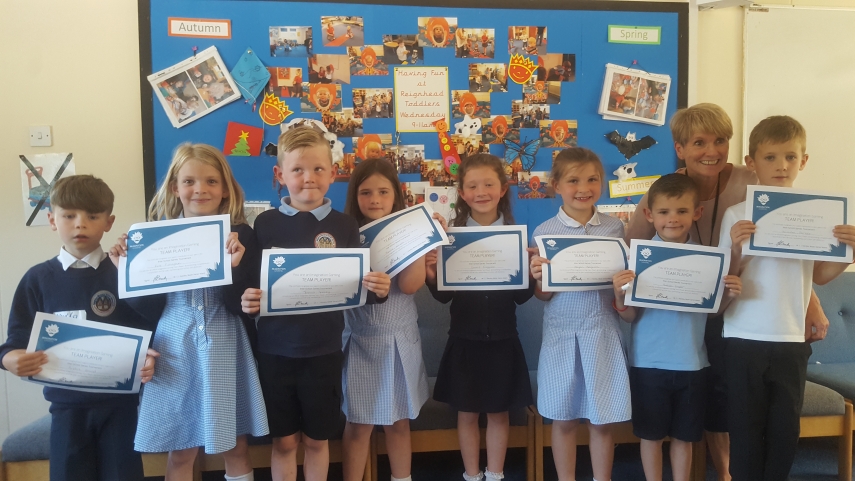 Eight children and their teacher all holding certificates