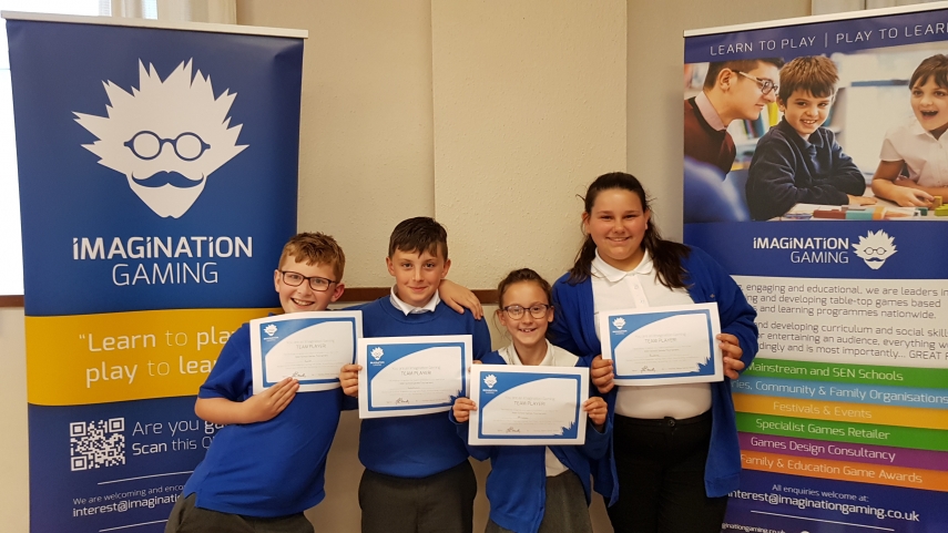 Four children wearing blue and white uniform holding Imagination Gaming certificates
