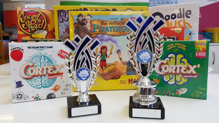 Game boxes stood on edge with two Imagination Gaming Trophies stood in front