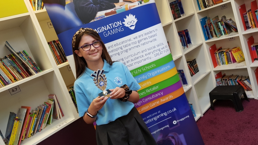 Girl holding trophy in front of Imagination Gaming roller banner