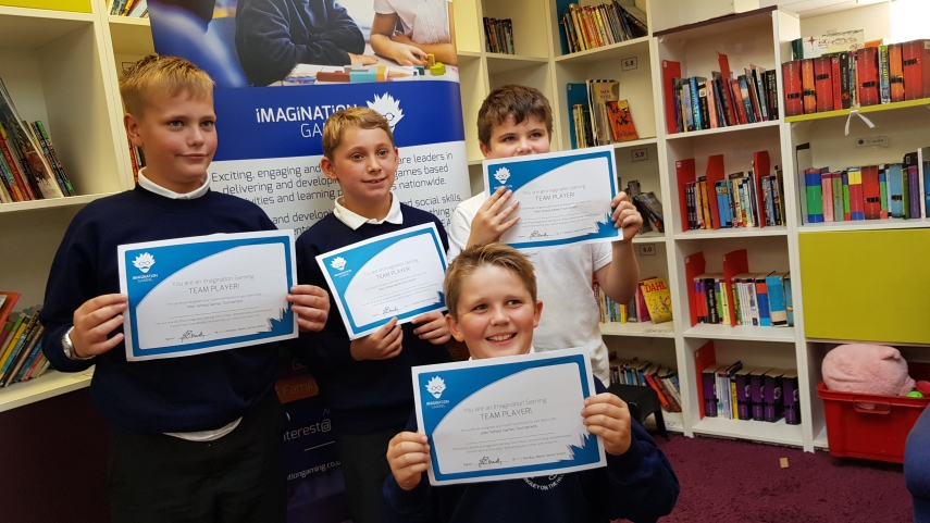 Four children holding certificates in front of Imagination Gaming
