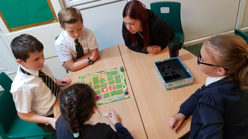 Pupils and teacher playing a board game on table top