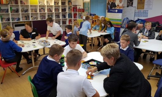 Groups of school pupils and teachers sat at tables playing board games together