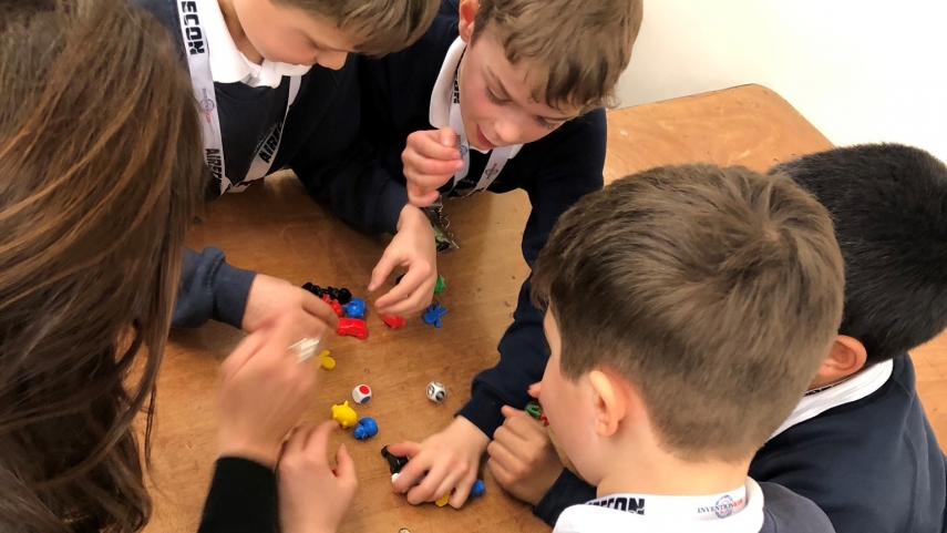 Five children gathered around table with dice and meeples