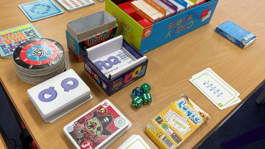 Games, cards and open boxes of games displayed on a desk.