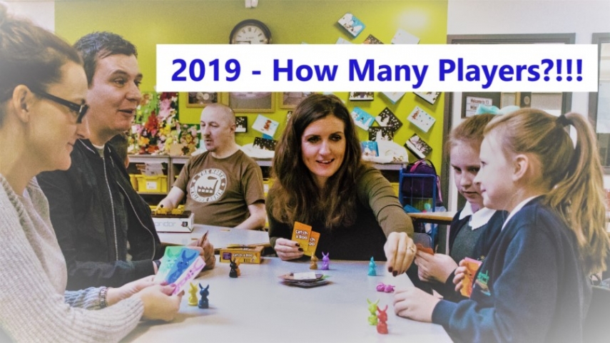 Image of adults and children playing card game with overlaid text reading "2019 - how many players?!!!"