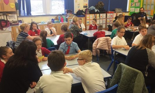 Group of students and teachers sat around desks playing games