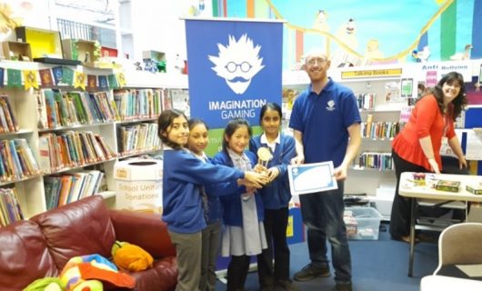 Group of school girls with certificate and trophy, stood next to a member of the Imagination Gaming staff